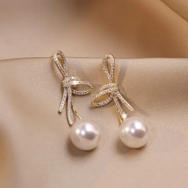 Pearl earrings with a glossy bow golden