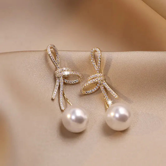 Pearl earrings with a glossy bow golden